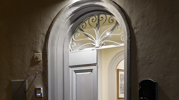 Une porte surmontée d’un arc décoratif, une boîte aux lettres et un luminaire fixé au mur.