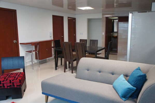 Una sala de estar con un sofá, una mesa de comedor con sillas y una zona de kitchenette.