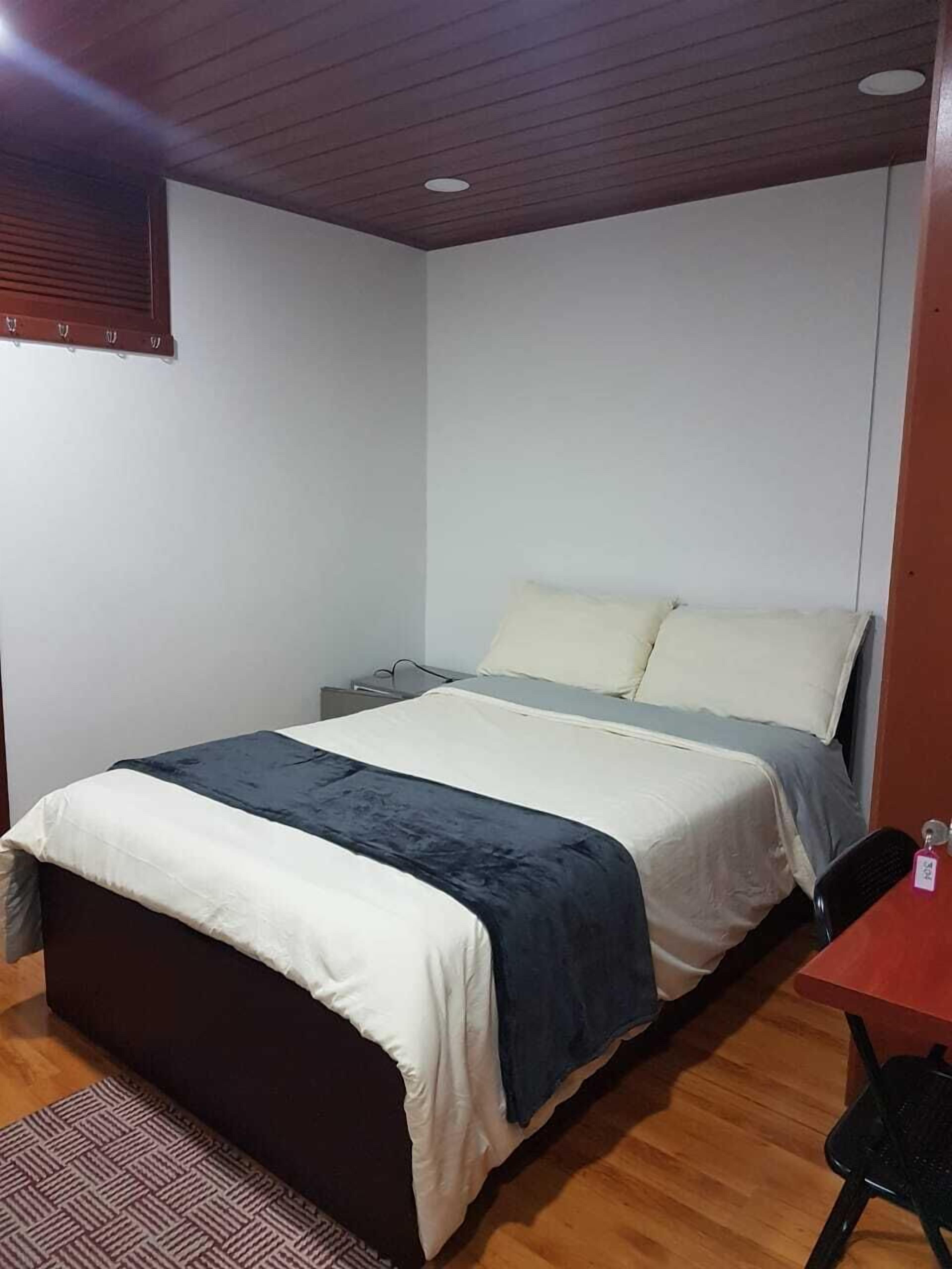 Une chambre à coucher avec un lit, des tables de chevet, une chaise et un plancher en bois.