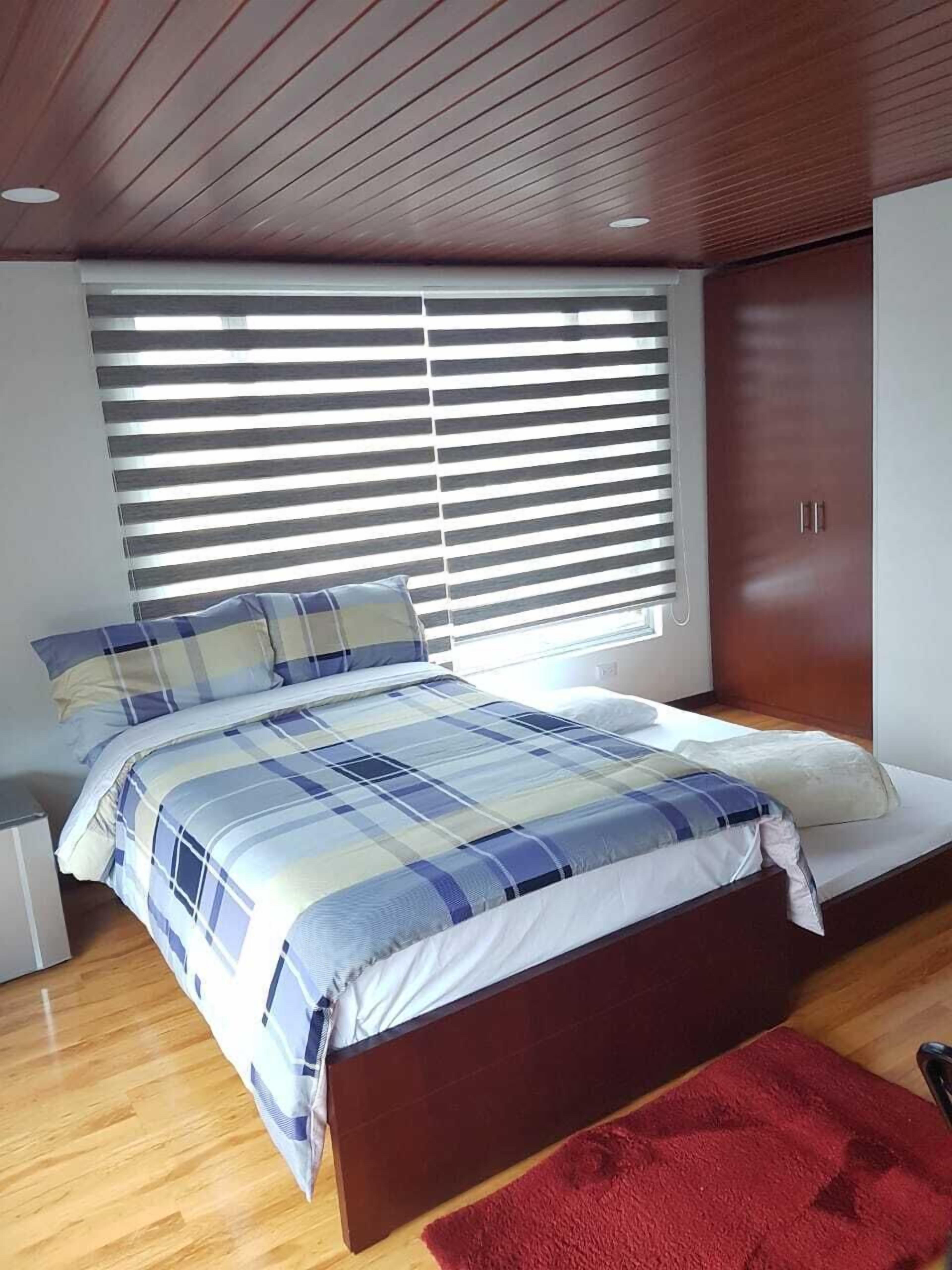 Une chambre moderne avec un grand lit, un plafond en bois et une armoire.