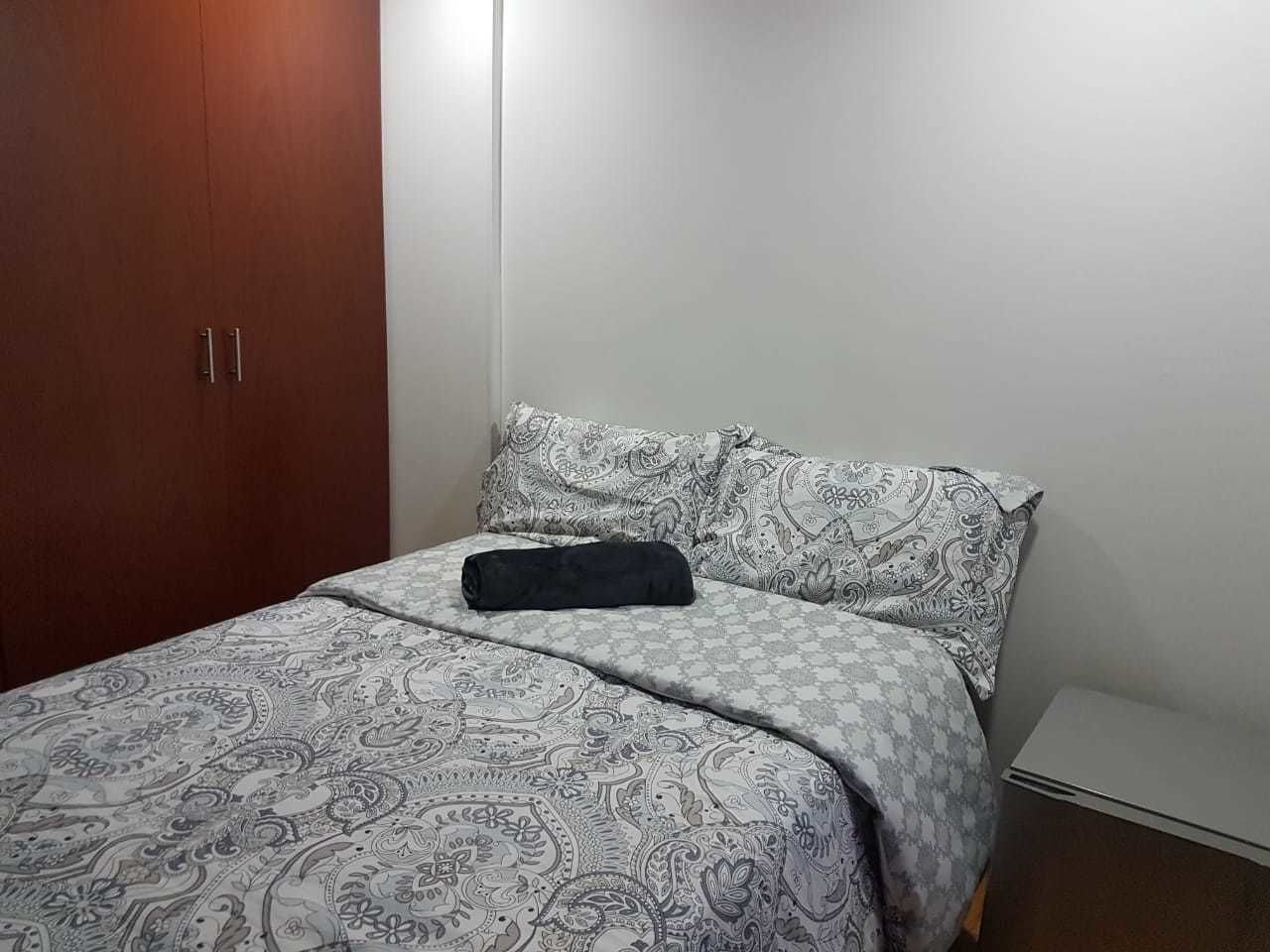 Un dormitorio con cama, armario y pared blanca.