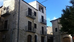 Una calle estrecha con edificios de piedra, algunos con balcones y arcos.