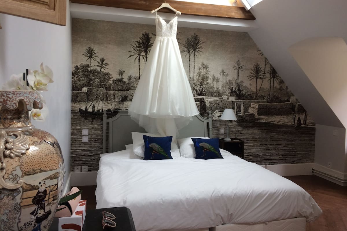 A bedroom with a bed, a decorative vase, and a mural on the wall.