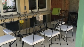 An outdoor patio with a glass-top table and metal chairs.