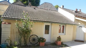 A house with a tiled roof, a front door, and potted plants.