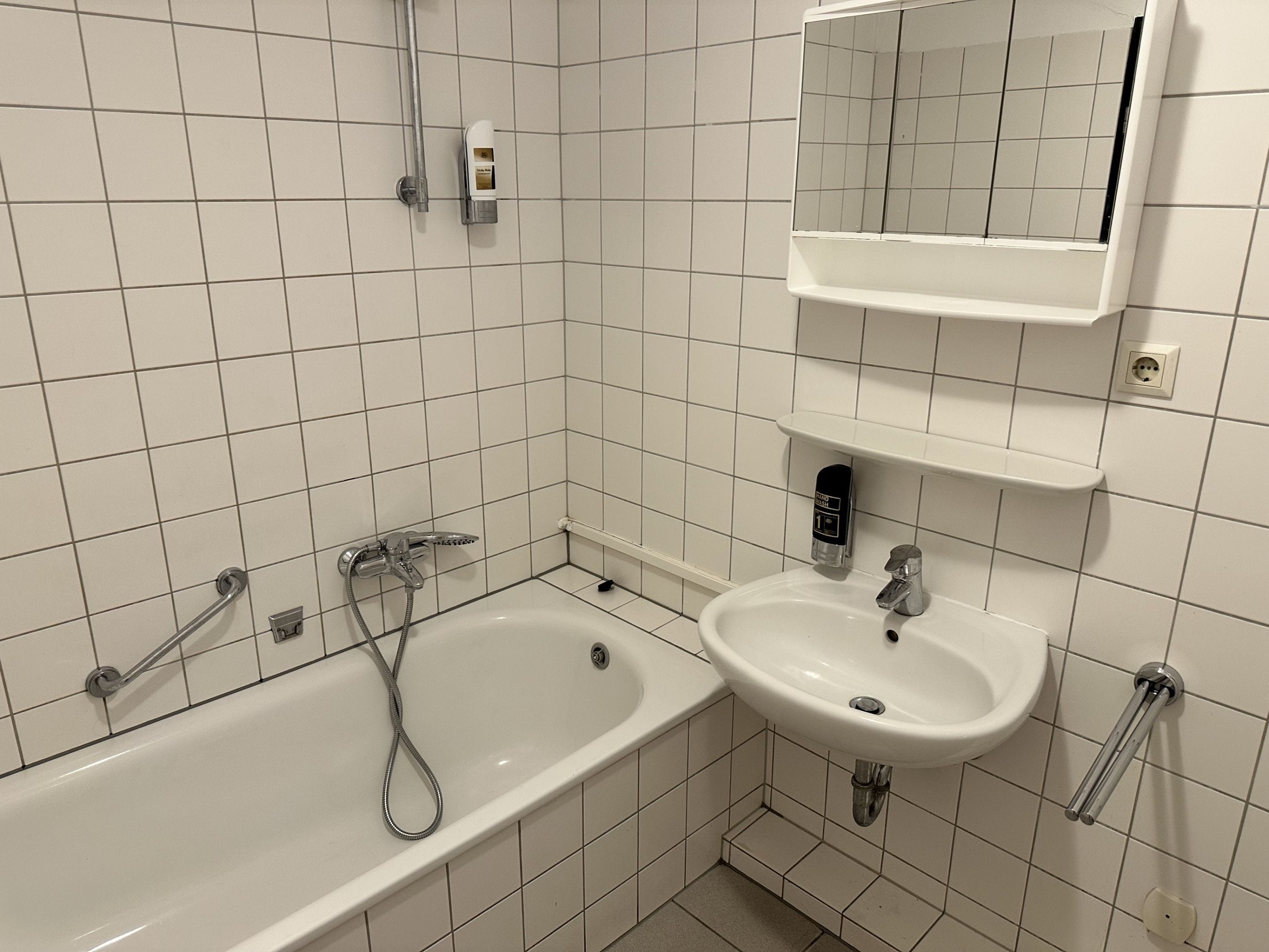 Een badkamer met een bad, wastafel en spiegel.