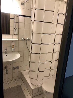 A modern bathroom with a white tiled wall, a white sink, and a shower enclosure. - Hotel Bayrischer Hof (Krefeld)