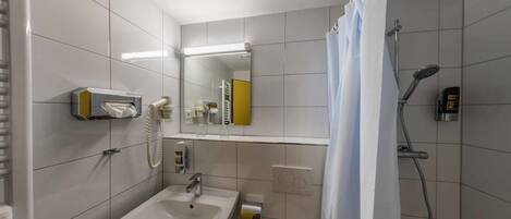 A modern bathroom with a sink, mirror, and shower.