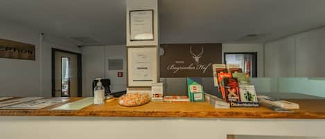 A reception desk with a framed certificate, a clock, and various informational materials.