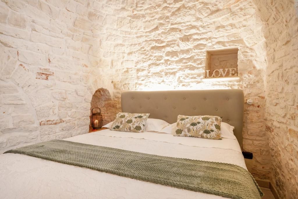 A bedroom with a stone wall, a bed with floral pillows, and a 'LOVE' sign above the headboard.