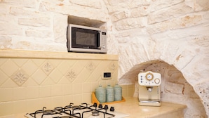 A kitchen with a gas stove, a microwave, and a coffee machine. - Trulli Di Zia Vittoria (Alberobello)