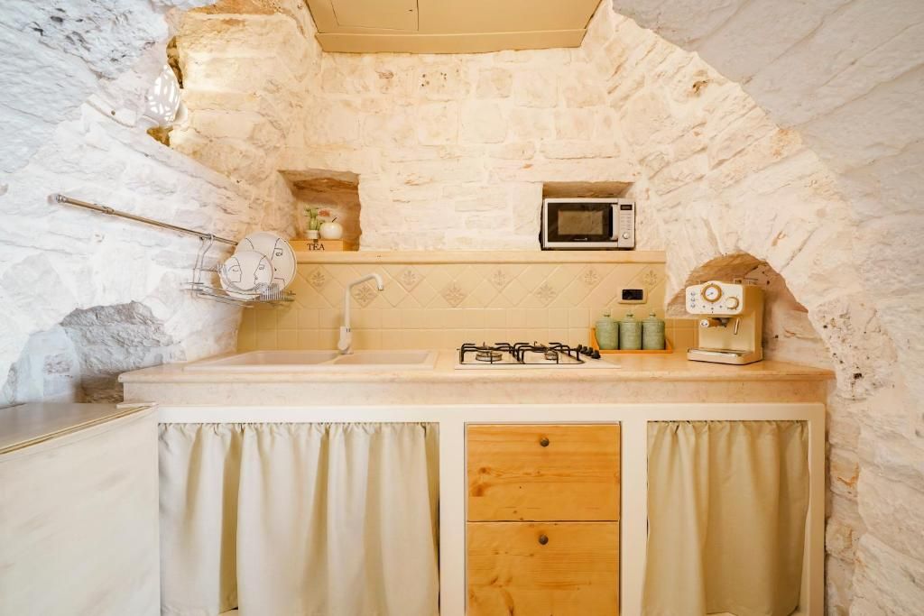 Una cocina con pared de piedra, microondas, estufa a gas y un lavabo.