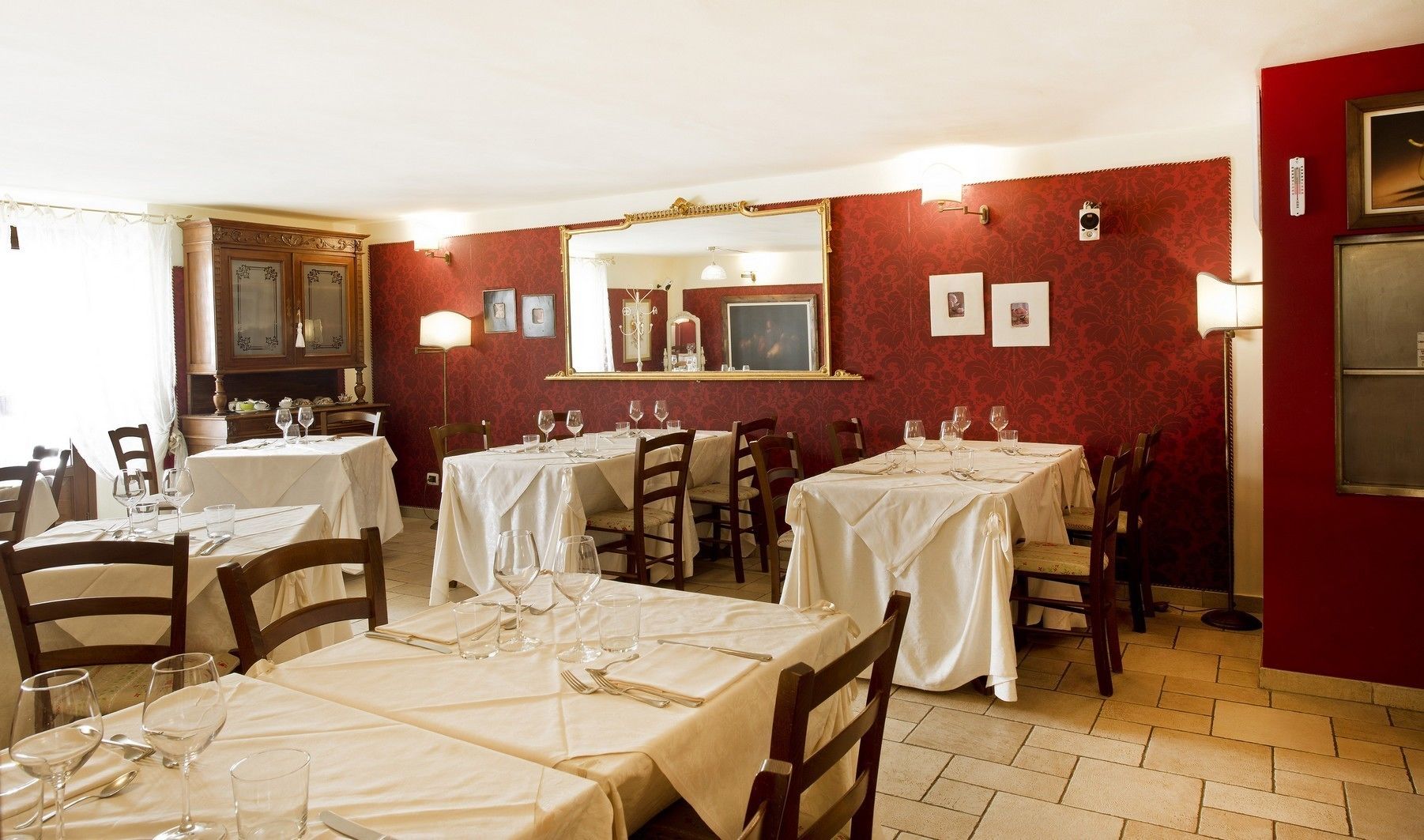 A restaurant with multiple tables set for dining, each with wine glasses and cutlery.