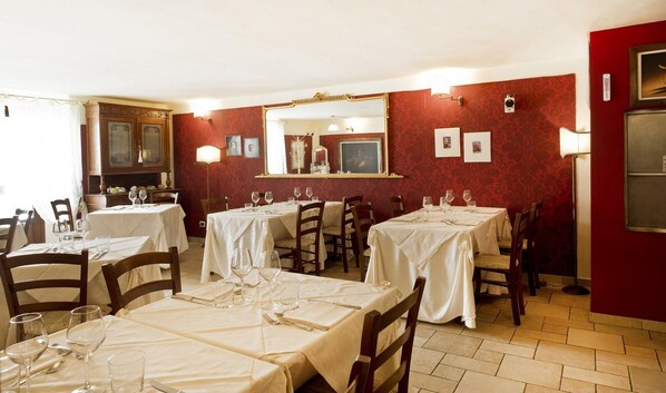 A restaurant with multiple tables set for dining, each with wine glasses and cutlery. - Residence La Pera Bugiarda (Venaria Reale)