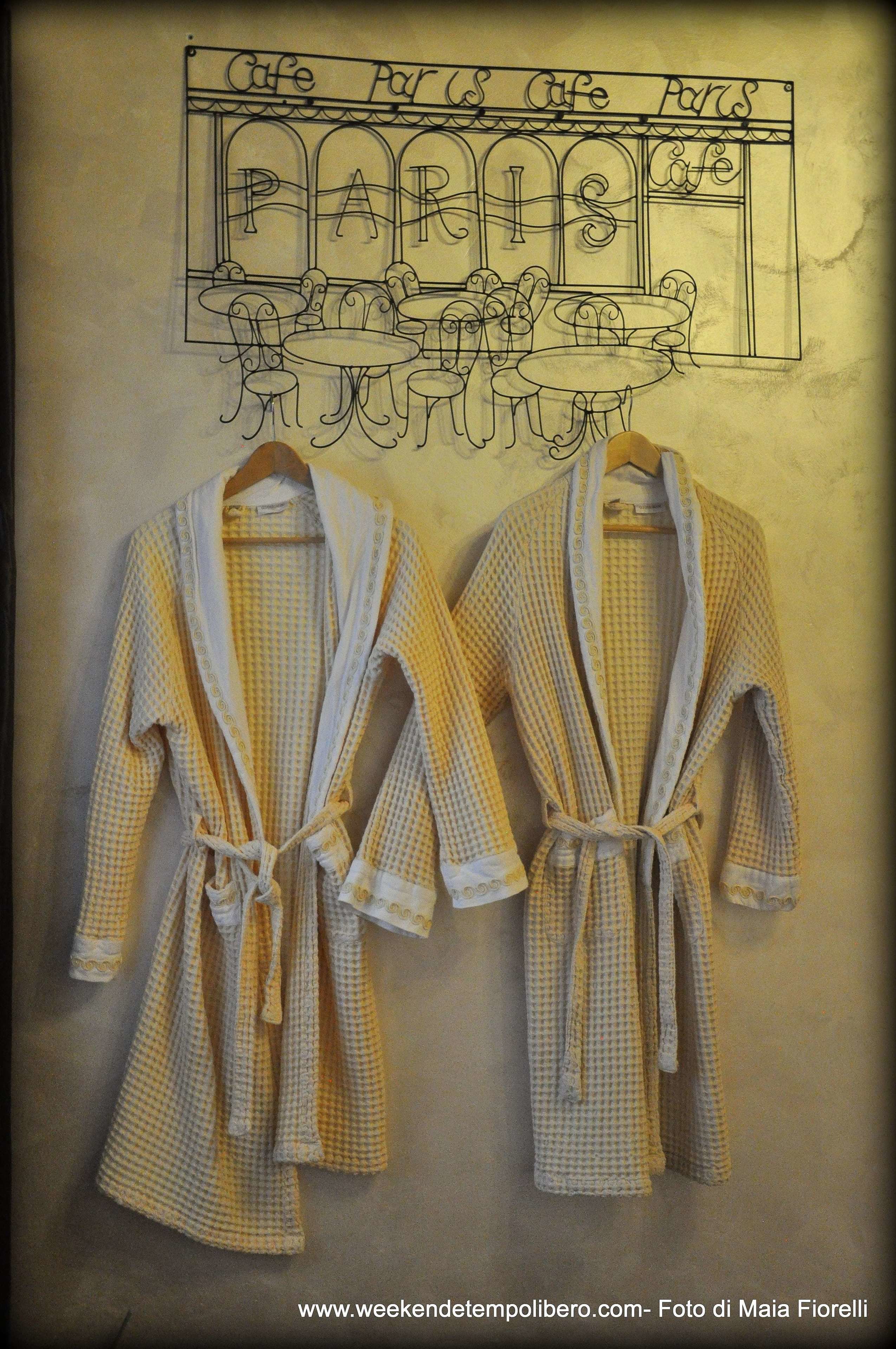 Two yellow and white checkered bathrobes hanging on a wall with a sketch of a cafe named "Cafe Paris" above them.