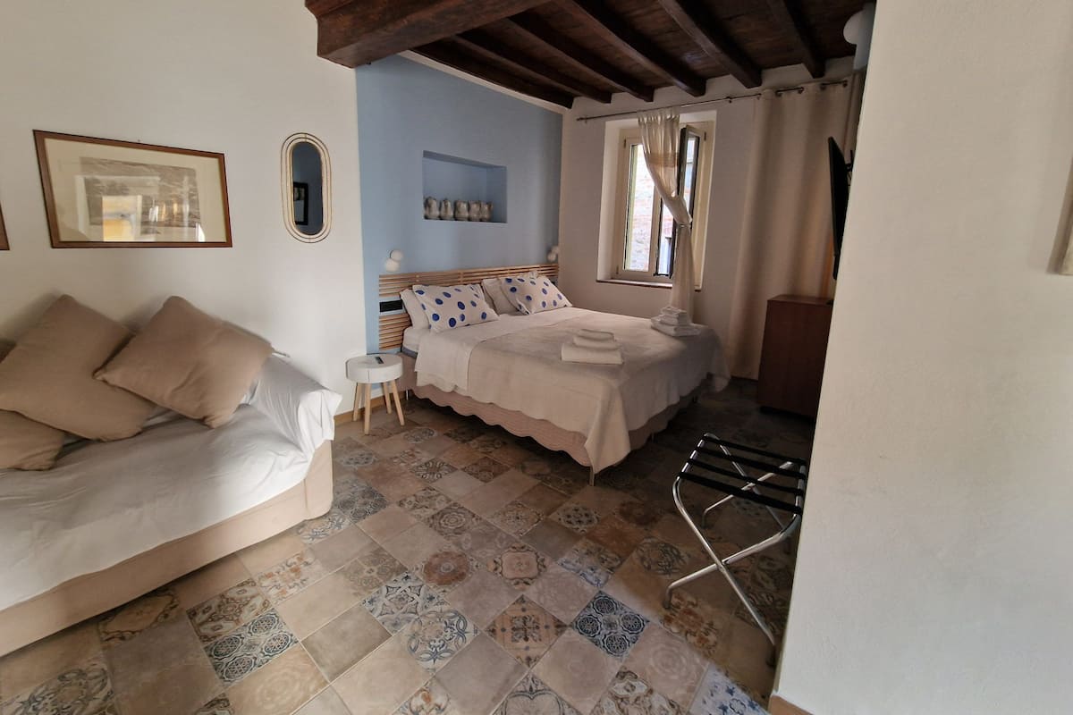 A bedroom with a bed, a nightstand, a chair, and a window with curtains.