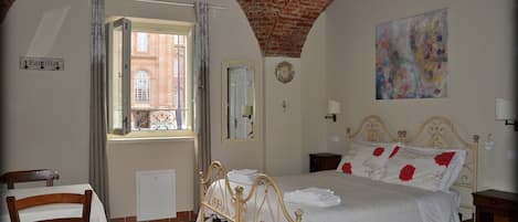 A bedroom with a bed, a chair, a window, a clock, and a painting.