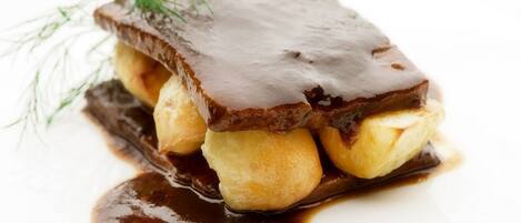 A dessert with a chocolate glaze, bananas, and a sprig of dill on a white plate.