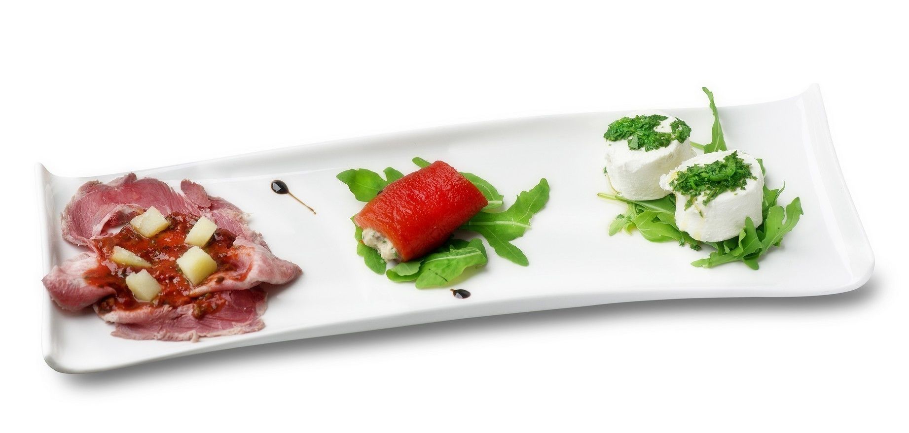 Plat blanc rectangular amb tres aliments: una làmina de carn amb cubs, una fragaria i dues culleradetes de crema blanca amb guarnició verda.