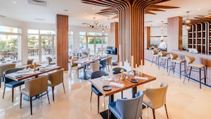 A modern restaurant with high ceilings, wooden accents, and a bar area.