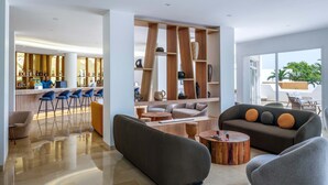 A modern hotel lobby with a bar area, seating, and a view of the outdoors.