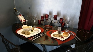 Mesa preparada para dos, con una botella de vino, copas y un candelabro con velas.