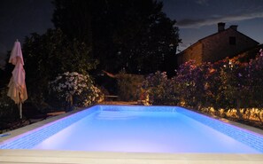 Een buitenzwembad, parasols bij het zwembad en ligstoelen