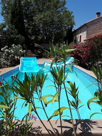 Una piscina al aire libre, sombrillas, sillones reclinables de piscina