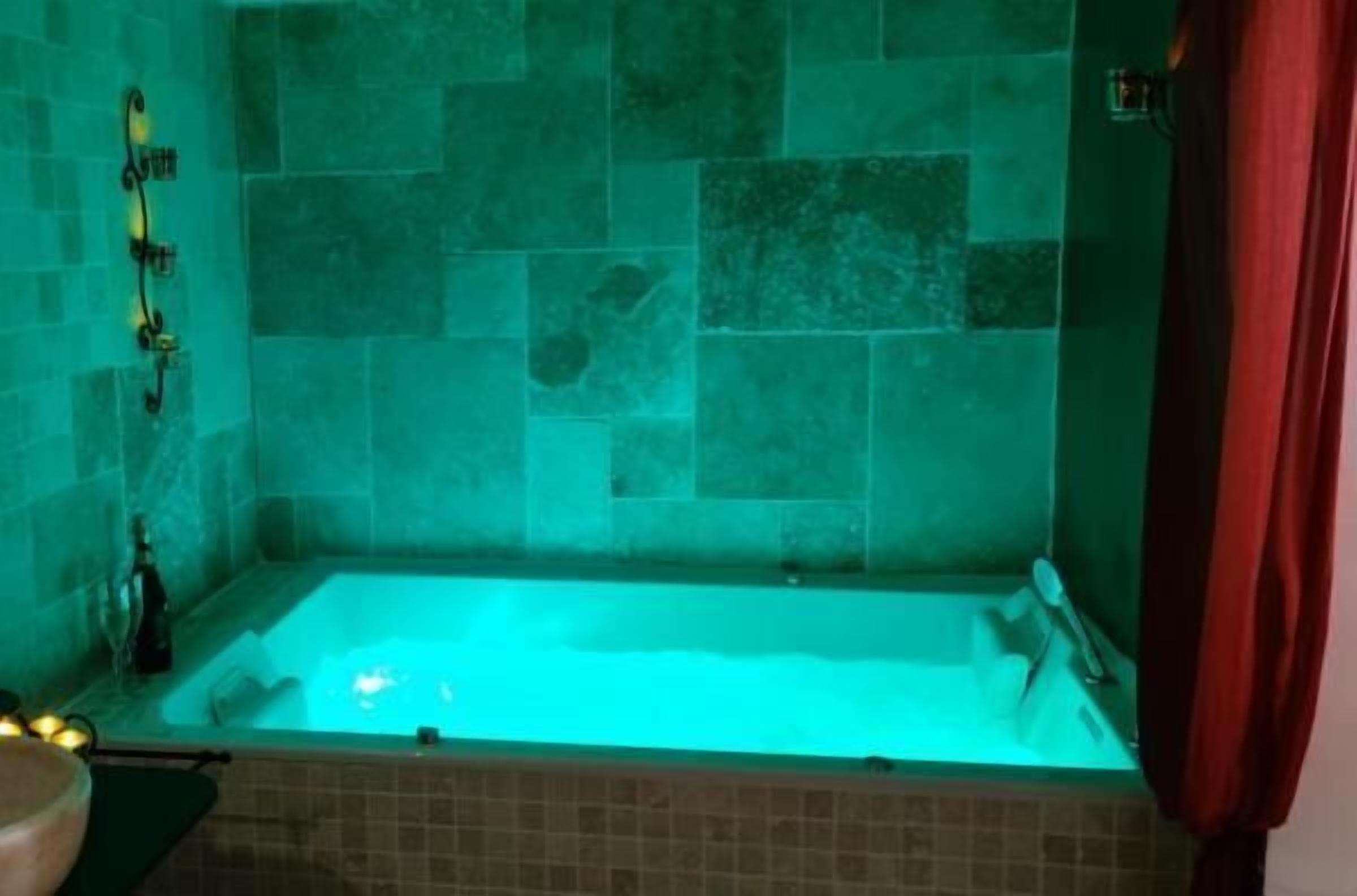 A bathroom with a bathtub, tiled walls, and a shower area.