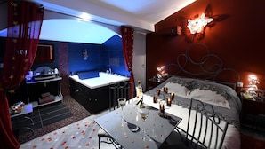 Un dormitorio con cama, una mesa con bebidas, un baño con bañera y zona de ducha.