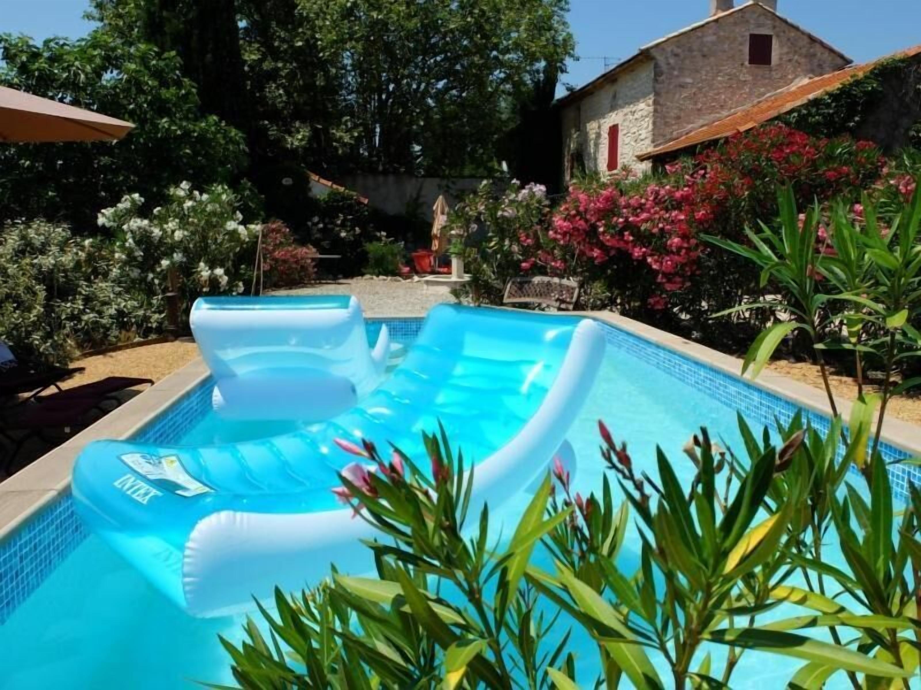 Una piscina al aire libre, sombrillas, sillones reclinables de piscina