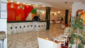 Un vestíbulo de hotel con mostrador de recepción, zona de estar y letrero de recepción.