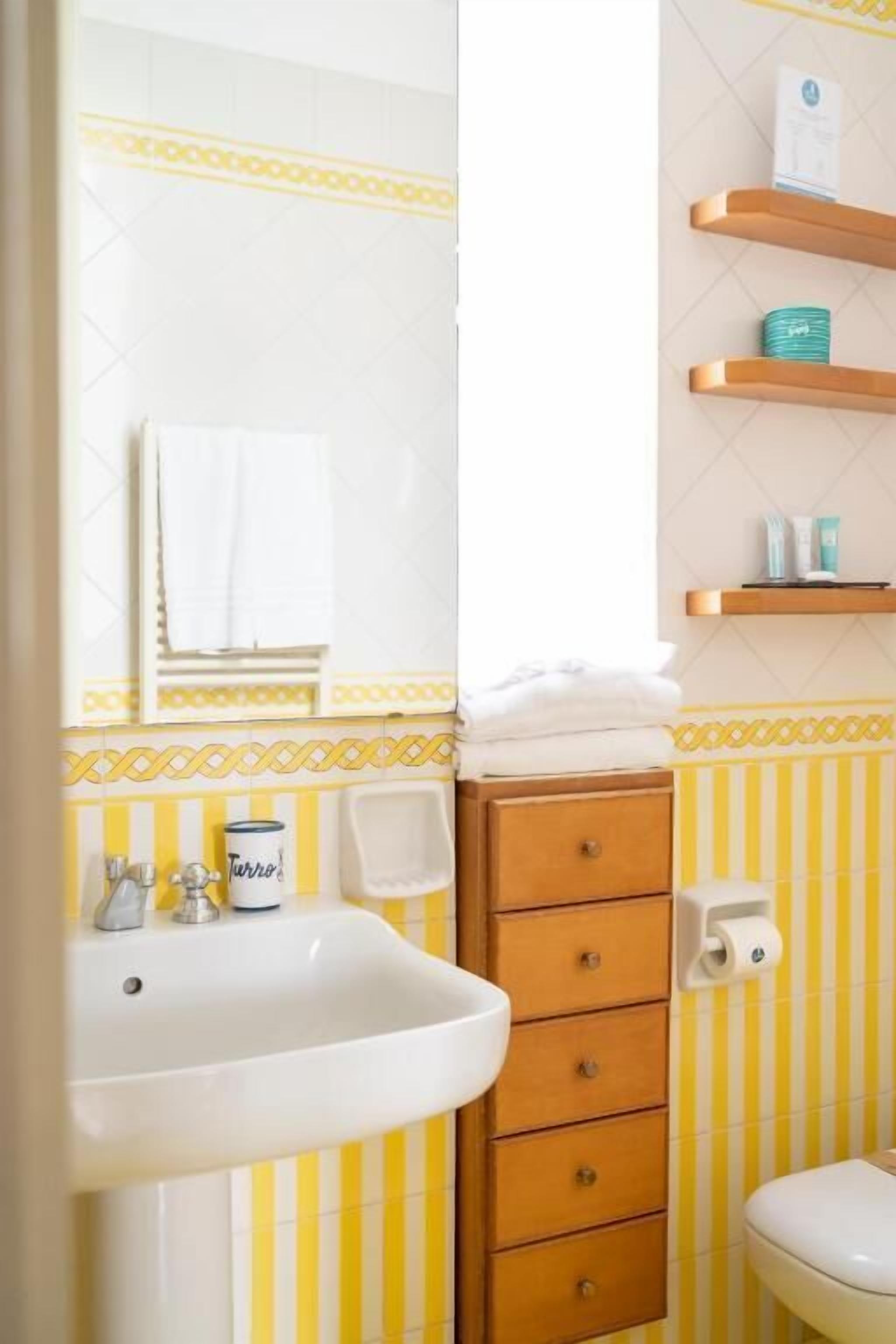 A bathroom with a white sink, wooden cabinet, and striped yellow and white tiles.
