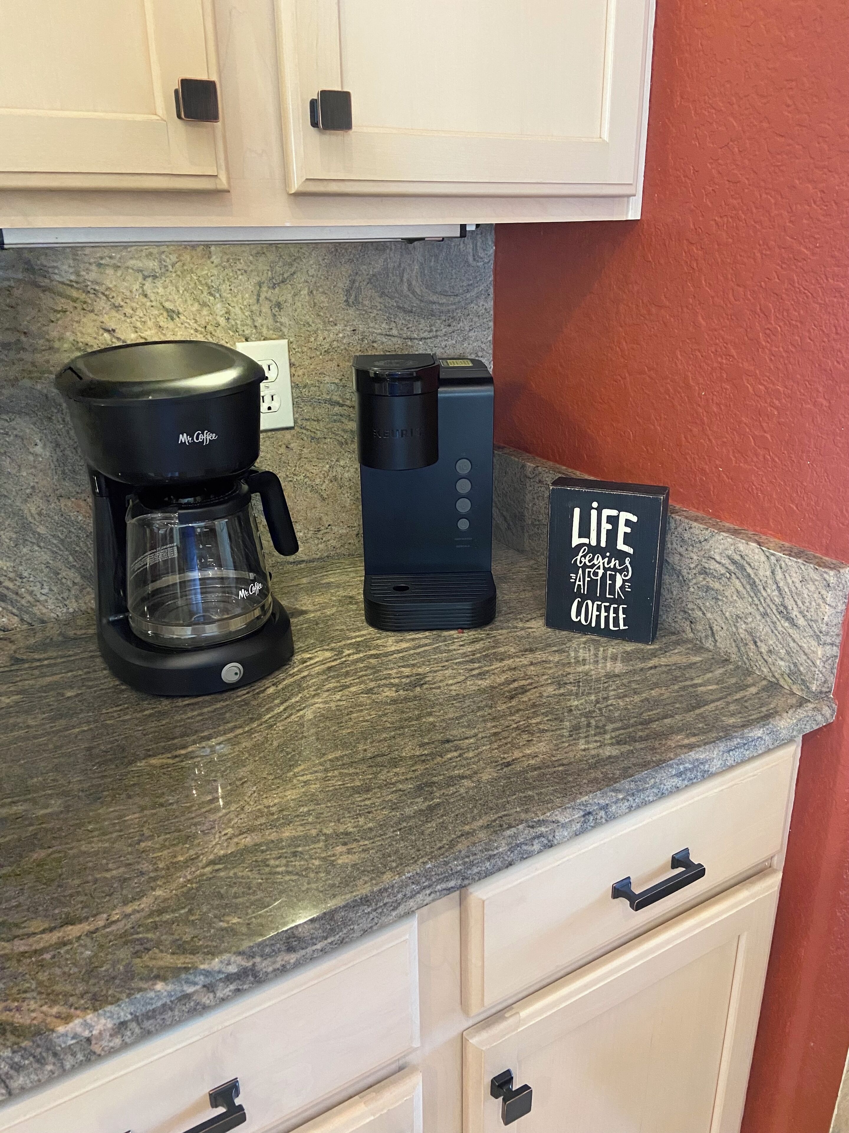 A kitchen counter with a coffee maker, a coffee machine, and a sign that says "Life begins after coffee."