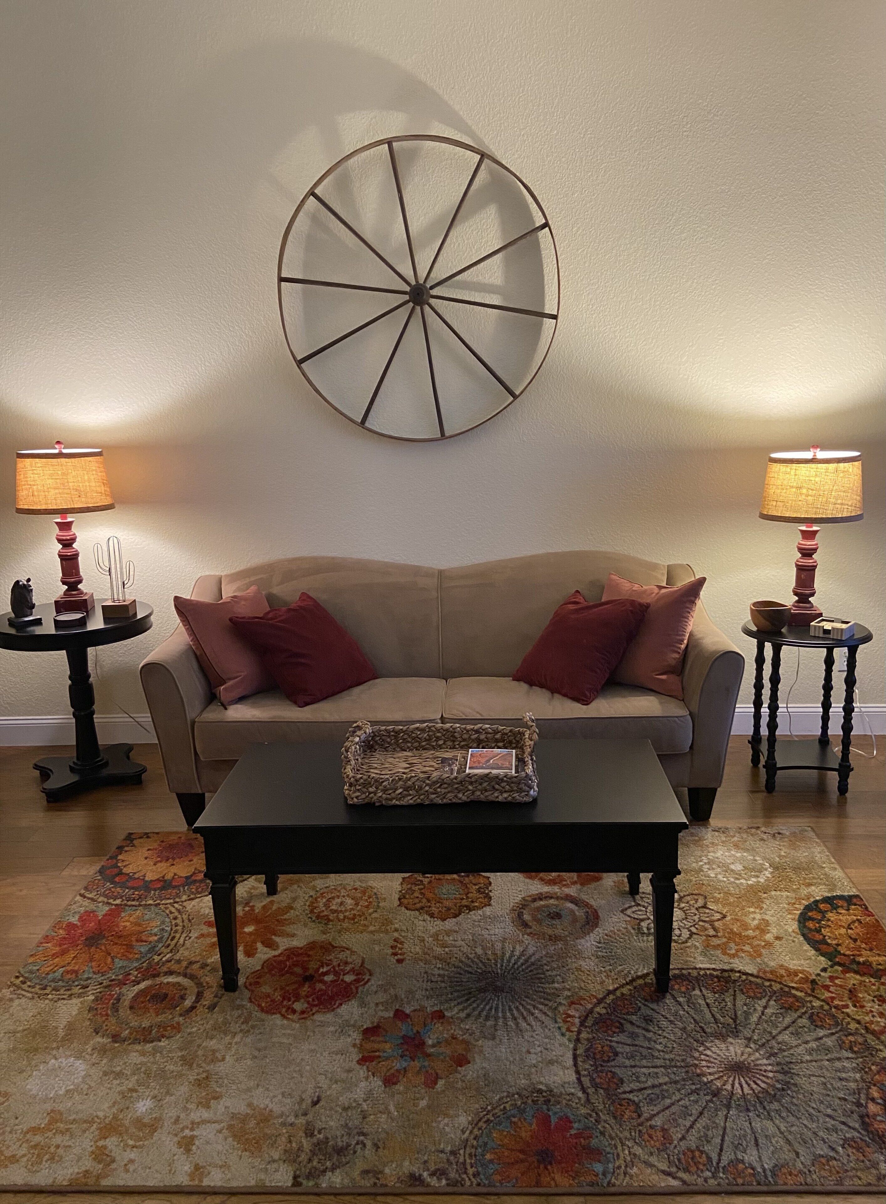 Ein Wohnzimmer mit Sofa, Couchtisch, Wanddeko, zwei Lampen und einem gemusterten Teppich.
