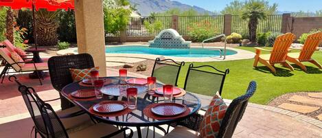 A patio with outdoor furniture, a pool, and a mountain view.