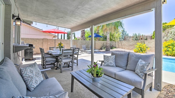 An outdoor patio with a covered seating area, a barbecue grill, and a pool in the background. - Pool & Putting Green: Scottsdale Family Escape (Scottsdale)