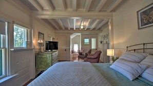 Un dormitorio con una cama grande, un aparador, una televisión y una silla.