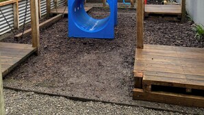 Ein Spielplatz mit Rutsche, Klettergerüsten und einer Schaukel mit Reifen.