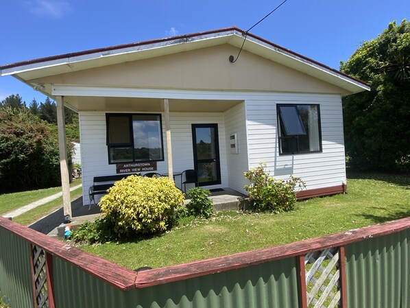 A single-story house with a porch, a sign reading "Arthurstown River View House," and a small garden area with bushes.