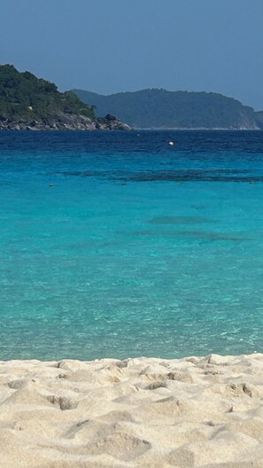 A beach with clear turquoise water, a sandy foreground, and a distant mountain range. - House / Villa - LE TIGNET (Le Tignet)