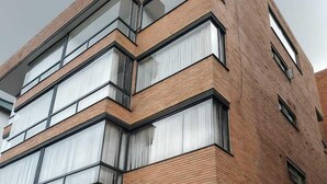 Un edificio de varios pisos con fachada de ladrillo, ventanas amplias y una tienda visible en la planta baja.