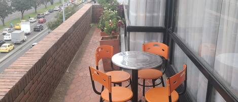 A balcony with a table and chairs, a brick wall, and a view of the city.