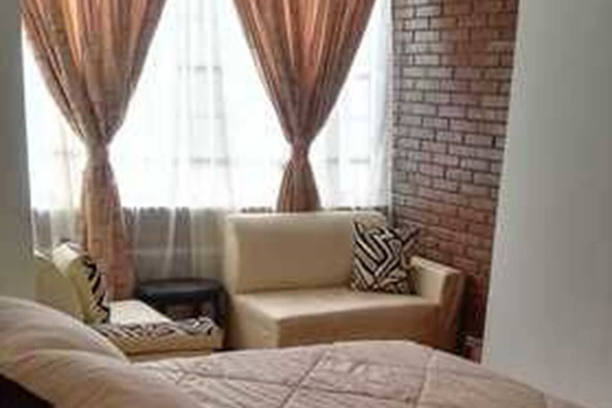 A bedroom with a large bed, a sofa, and a brick wall.