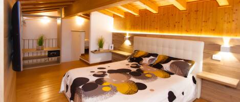 Un dormitorio moderno con techo de madera, una cama grande con colcha estampada, mesitas de noche con lámparas y una pequeña planta en la mesita.
