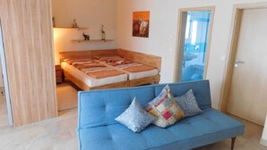 A bedroom with a bed, a blue sofa, and a wooden wardrobe. - Appartement am Rosengarten (Füssen)