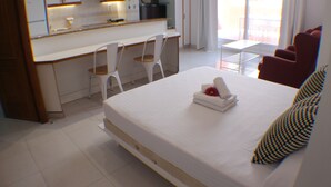 A hotel room with a bed, a desk, two chairs, a small table, and a balcony view. - Pi Sunyer 4 4B - Studio Apartment, Sleeps 2 (Roses)