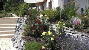 Une maison avec un jardin de pierres, un balcon en bois et un auvent blanc.