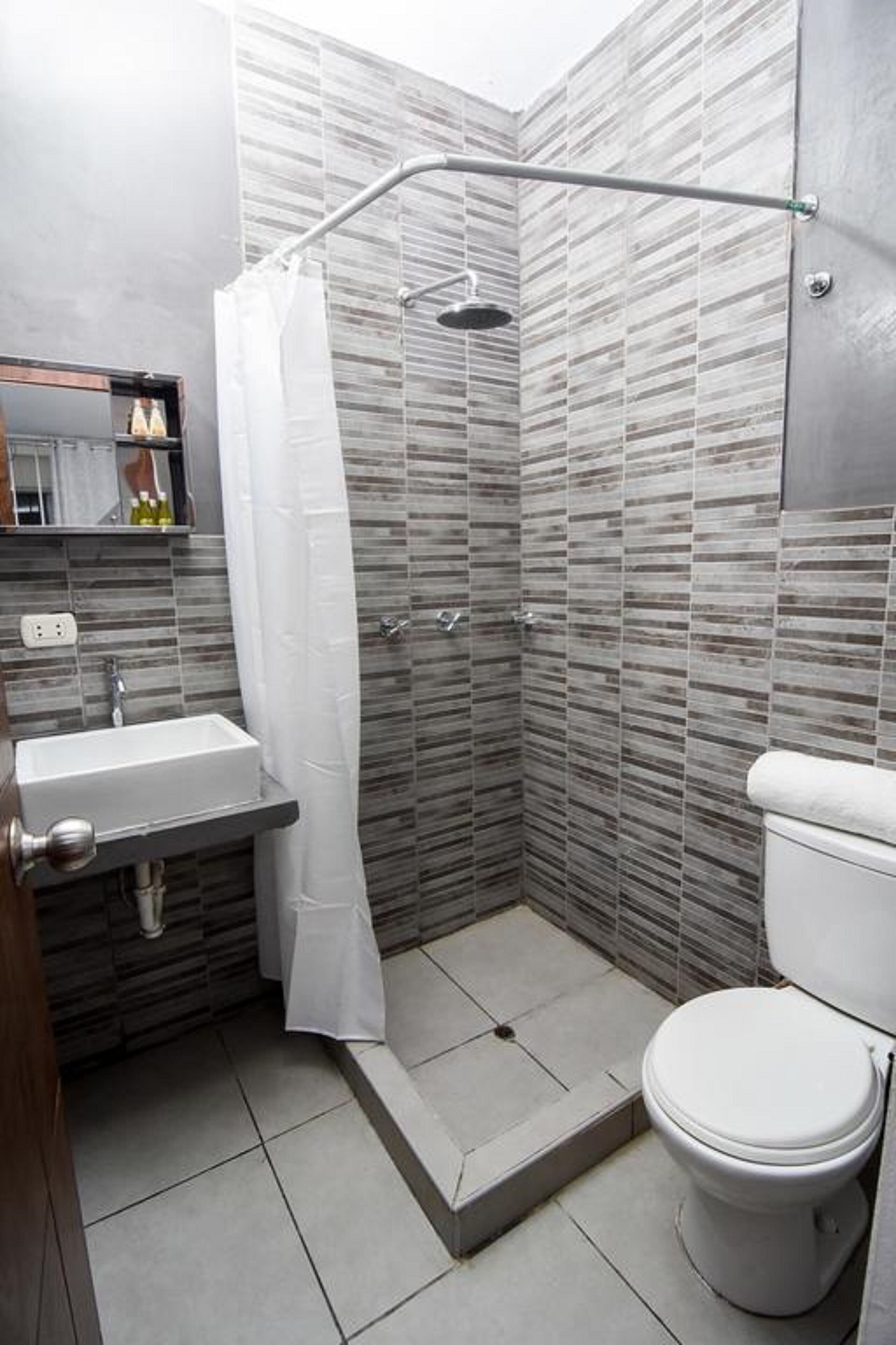 Un baño pequeño con ducha, inodoro y lavabo.