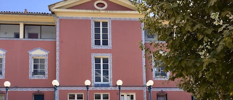 A building with a central staircase, multiple windows, and a decorative fountain in front.